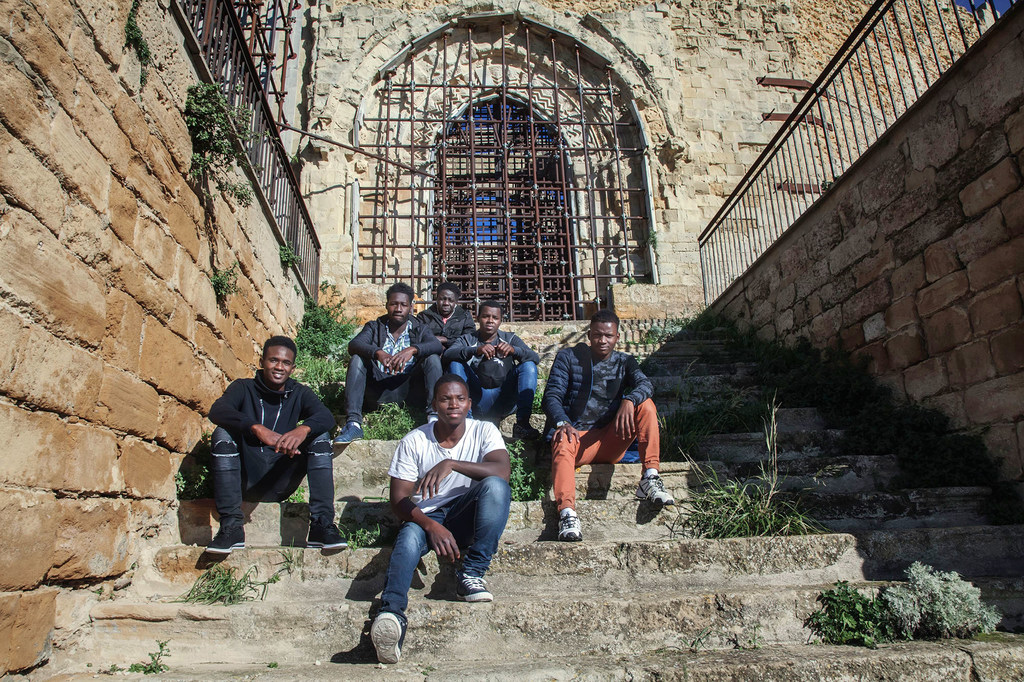 Photo : © UNICEF/Stefano De Luigi Omar (17 ans), à l'extrême droite au deuxième rang, et d'autres garçons migrants non accompagnés dans une église abandonnée en Sicile, Italie. La plupart d'entre eux ont été transférés sans choix dans ce petit village.